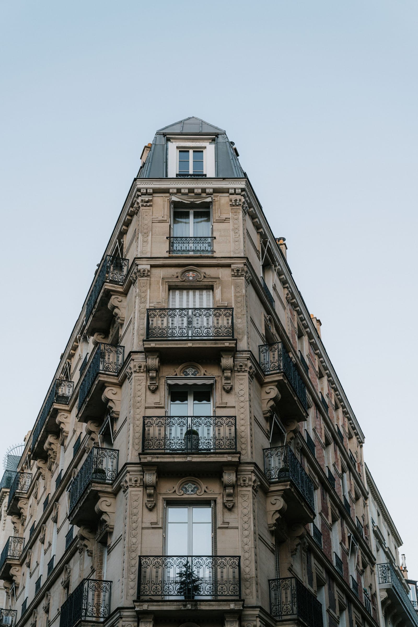 Immeuble d'angle en pierre de taille, façade et balcons en fer forgé.